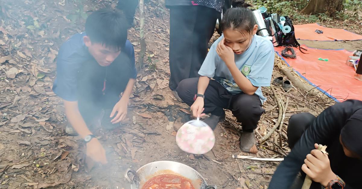 学生挑战在户外烹饪的生存技能。