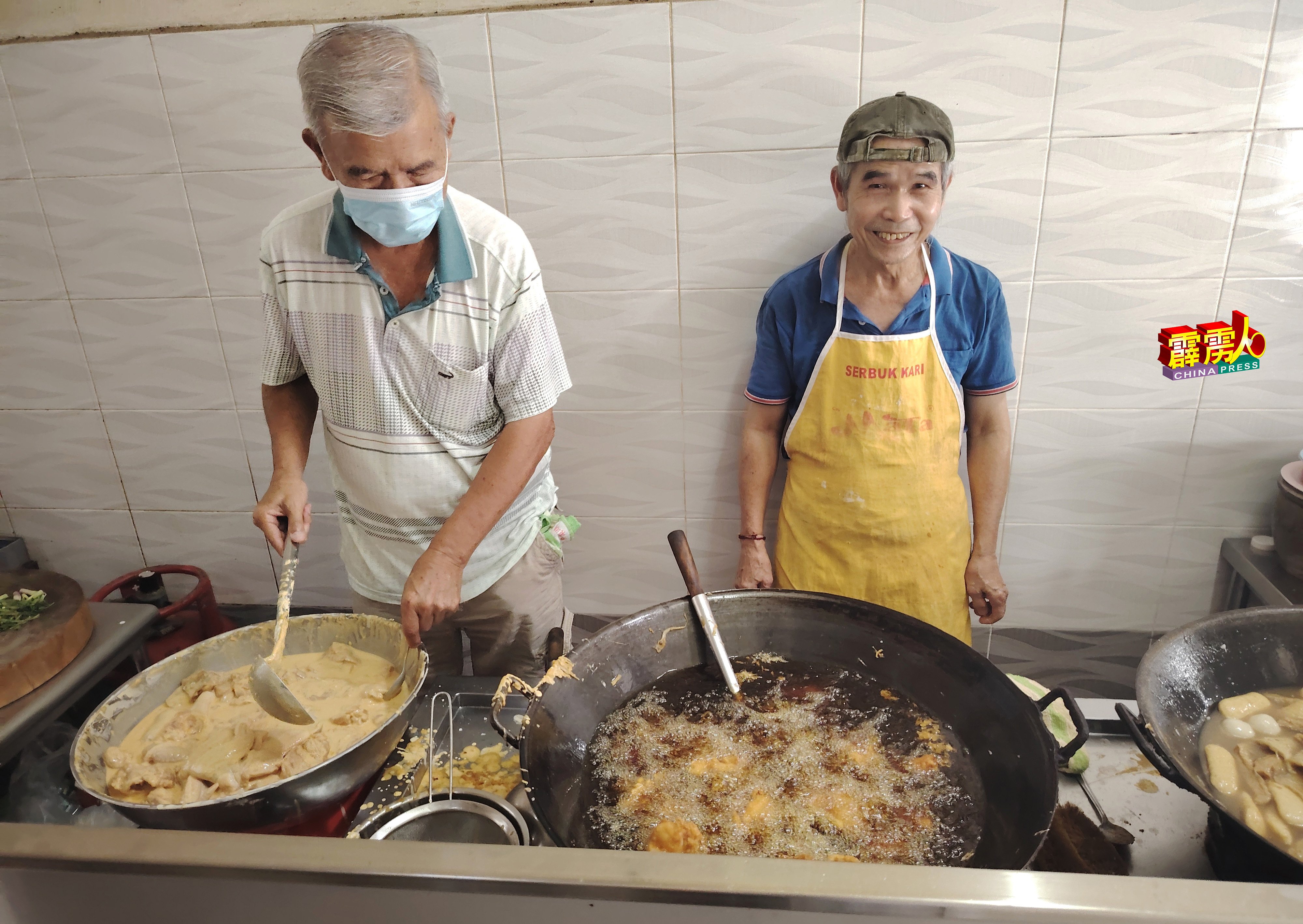 潘家建（右）和兄长潘家保在厨房忙着腌制及油炸鸡肉块