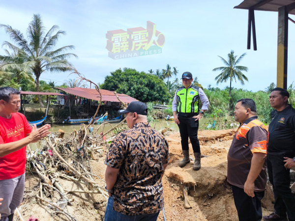 水利局官员再次到峇登村巡视拉律河缺堤情况，与吴锡标（左）研究挖河筑堤工程细节。