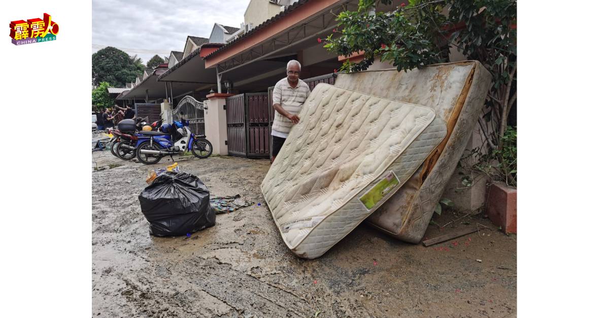 屋主一脸无奈地把浸损的床垫放在门前待清理。