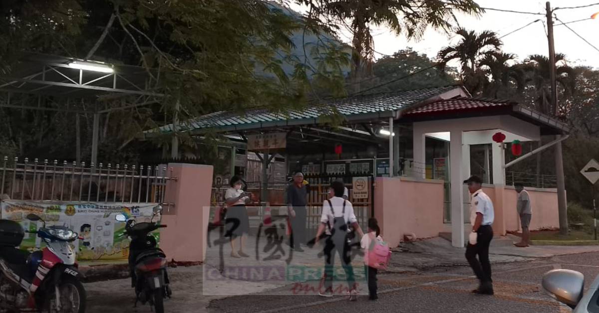 中华小学老师大清早站在学前，迎接学生返校。