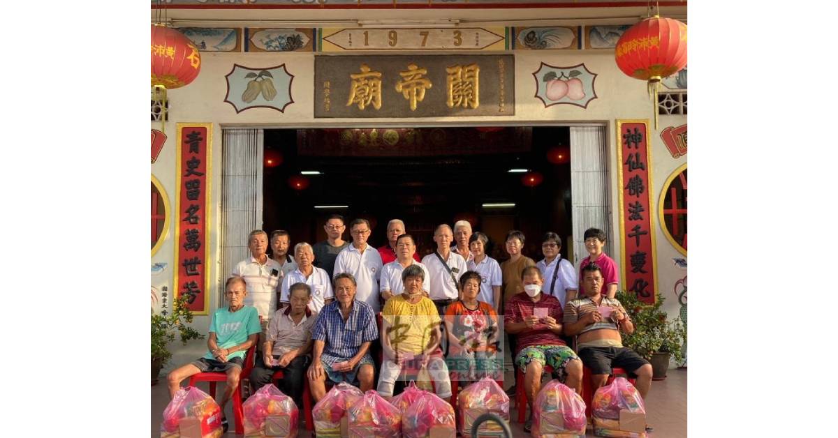 明德善社一行人到拱桥关帝庙，派发食品予拱桥新村13名弱势家庭的长者时在该庙前留影。