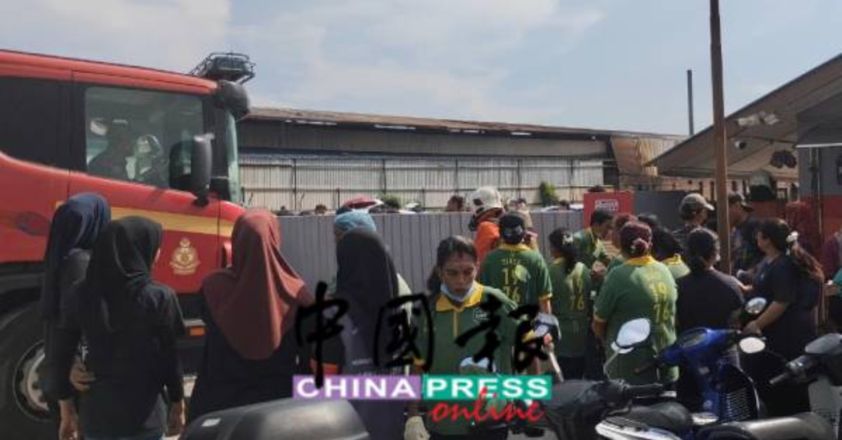 消防车(左)抵达时一度因电流中断致电动闸门无法打开而无法进入工厂范围内,图中尽管员工尝试人力推动也无效。