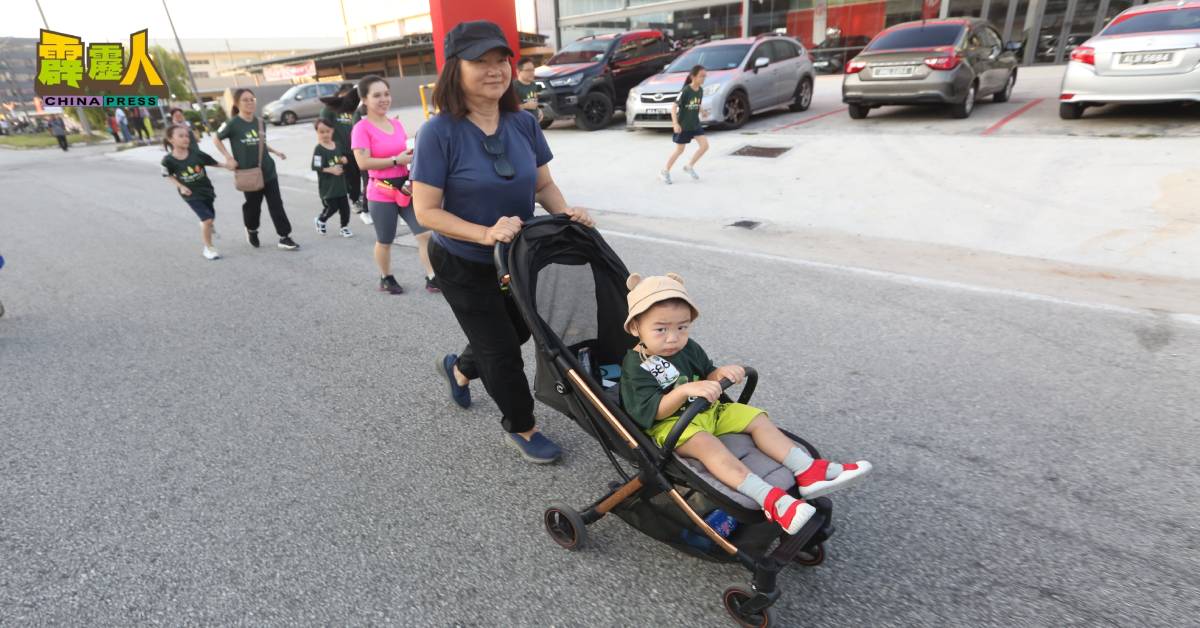 这名母亲用手推车载着幼小孩子一同参与公益路跑,从小培养环保意识。